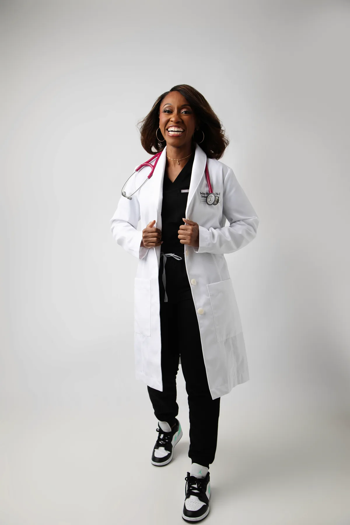 Fedna Morency laughing in a white coat with a pink stethoscope.